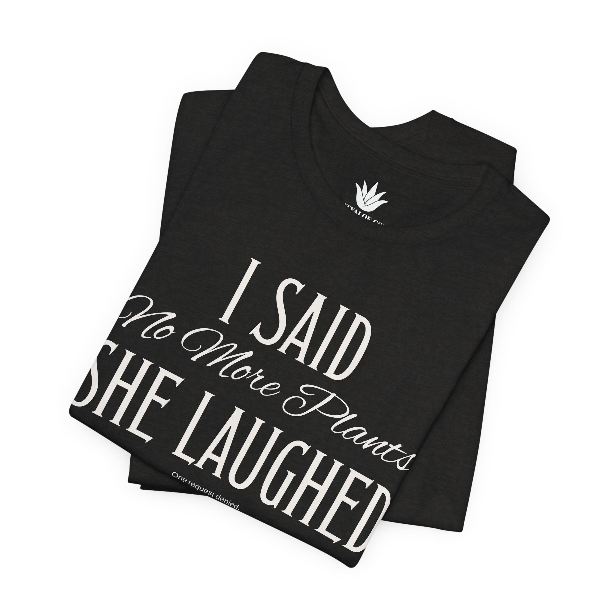 Black t-shirt with white vintage lettering that reads “I Said ‘No More Plants’ She Laughed,” a funny graphic tee for plant lovers and collectors. Folded.