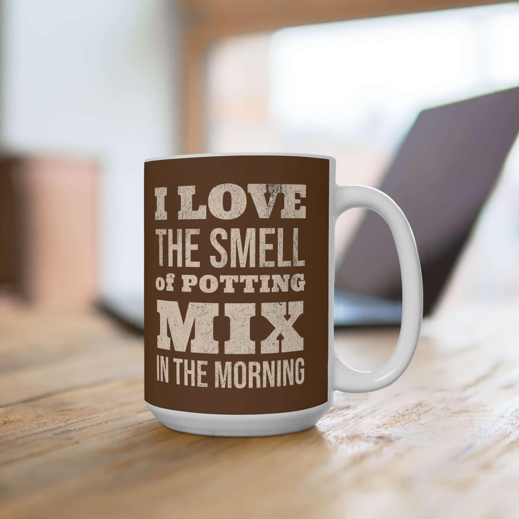 Mug with text 'I love the smell of potting mix in the morning' on a wooden surface.