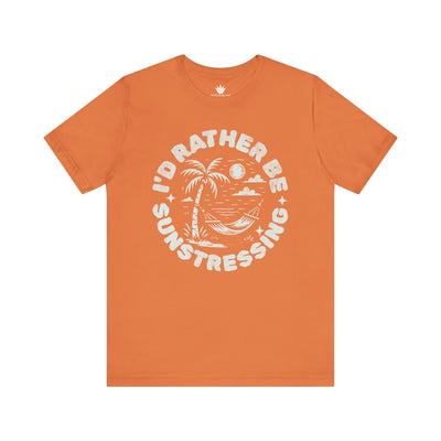 Orange t-shirt with white graphic and text 'I'd Rather Be Sunstressing' on a white background