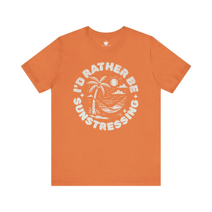Orange t-shirt with white graphic and text 'I'd Rather Be Sunstressing' on a white background