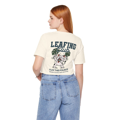 Person wearing a beige t-shirt with graphic design and text, standing against a white background