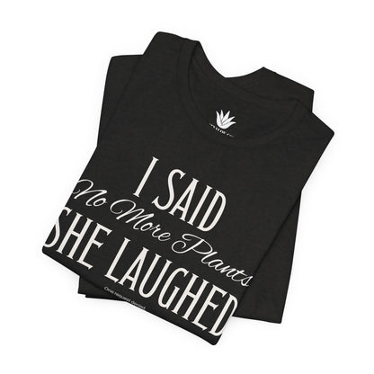 Black t-shirt with white vintage lettering that reads “I Said ‘No More Plants’ She Laughed,” a funny graphic tee for plant lovers and collectors. Folded.